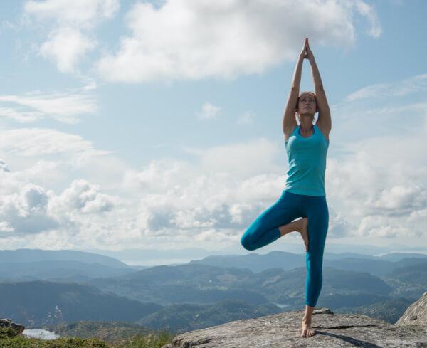 Een vrouw doet outdoor yoga op de top van een heuvel